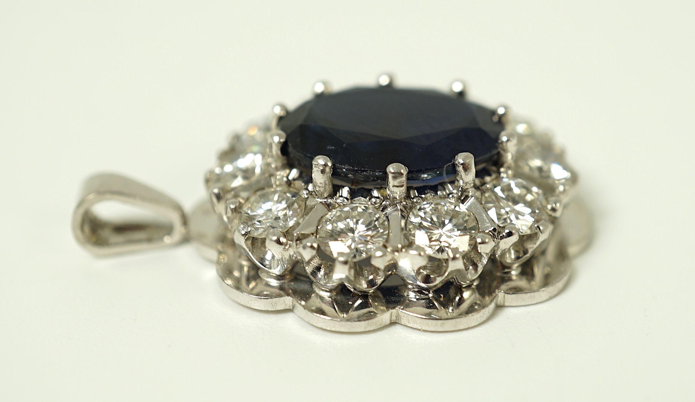 A modern 18ct white gold, sapphire and diamond set oval cluster pendant